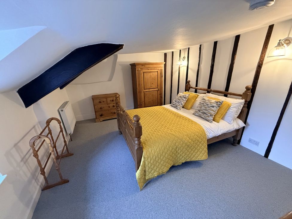 A bedroom with a bed and wooden furniture at Bridge Cottage in Chideock