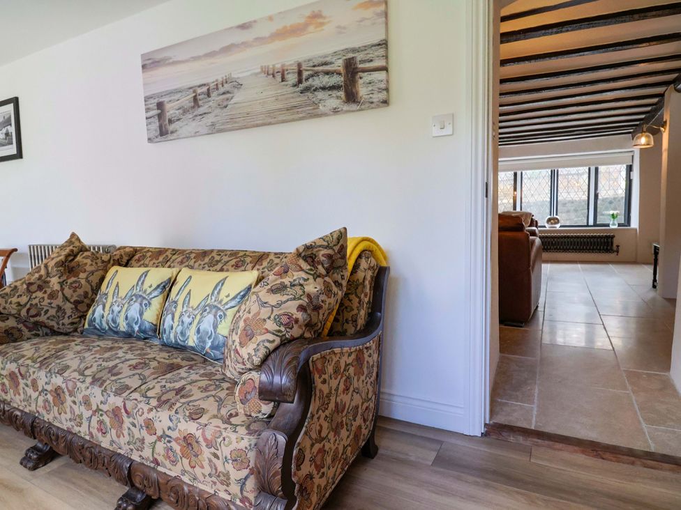 A living room with a sofa and artworks on the wall at Bridge Cottage in Chideock