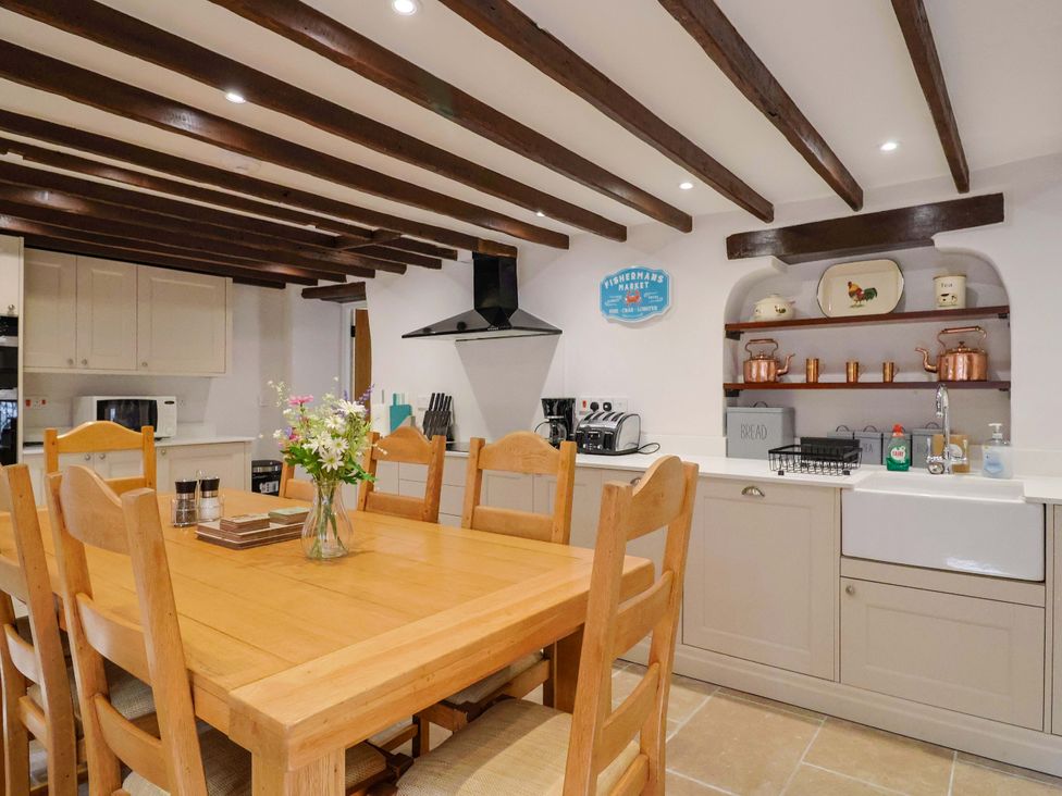 A kitchen featuring a dining table with chairs and kitchen appliances at Bridge Cottage in Chideock