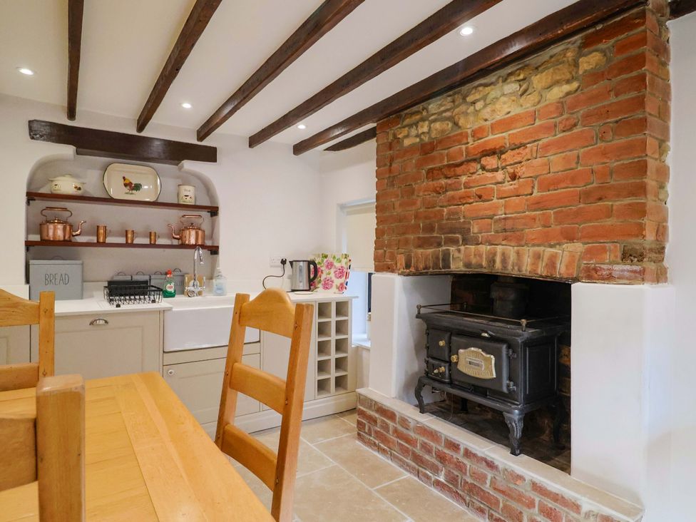 A kitchen with a stove and shelves at Bridge Cottage in Chideock