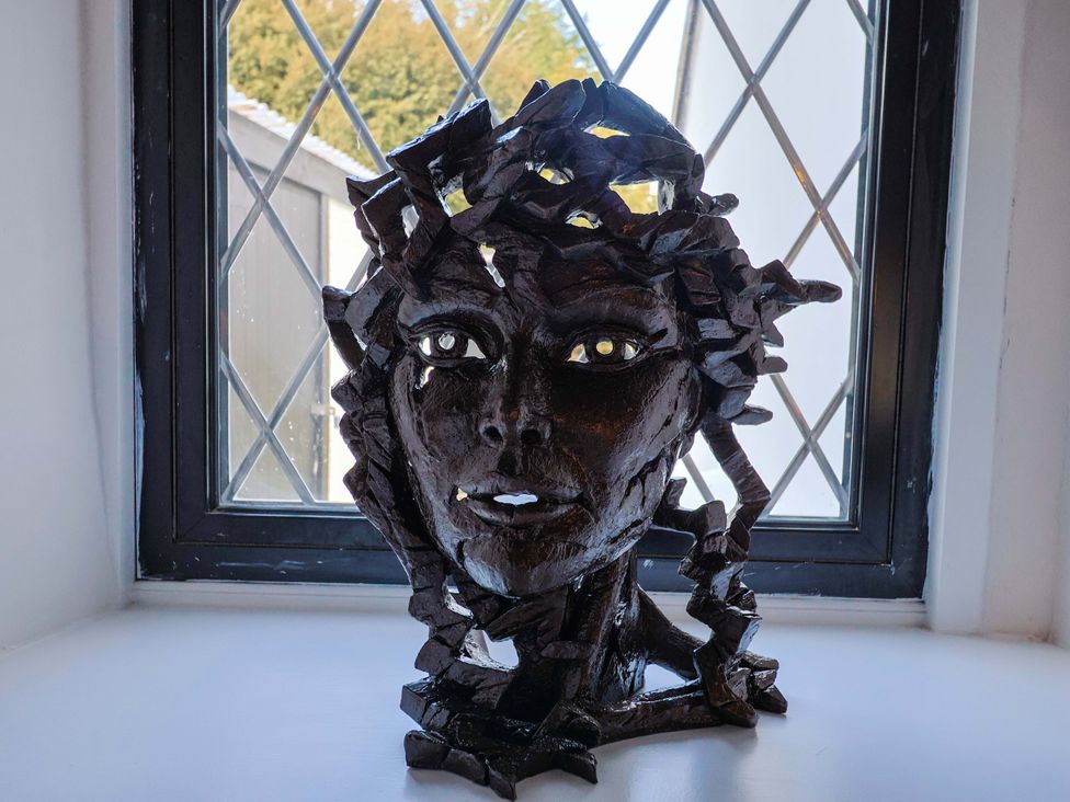 A sculpture of a face on a windowsill at Bridge Cottage in Chideock