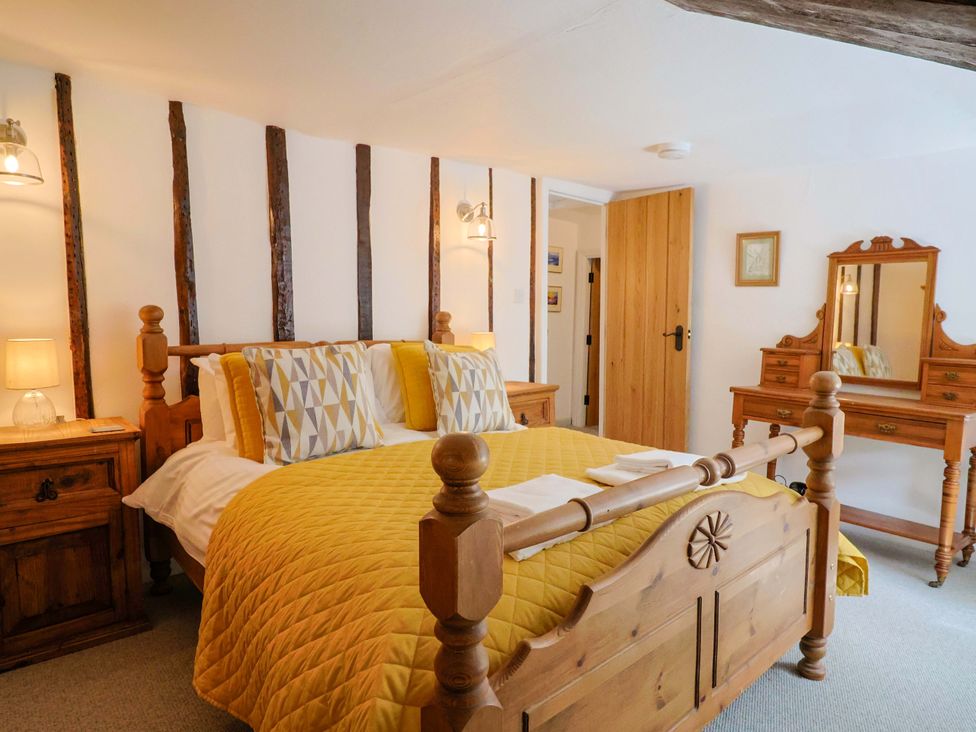 A bedroom with a bed, dresser, and mirror at Bridge Cottage in Chideock