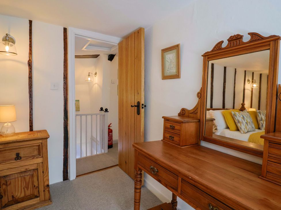 A bedroom with a wooden dresser and mirror at Bridge Cottage in Chideock