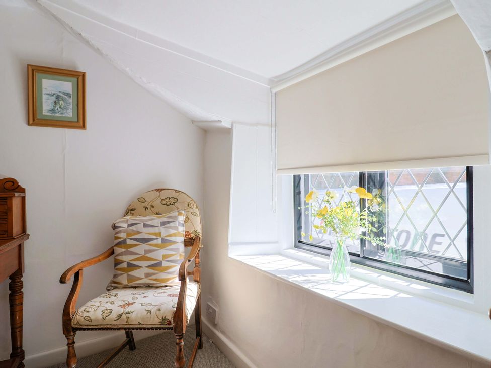 A seating area with a chair and flower vase at Bridge Cottage in Chideock