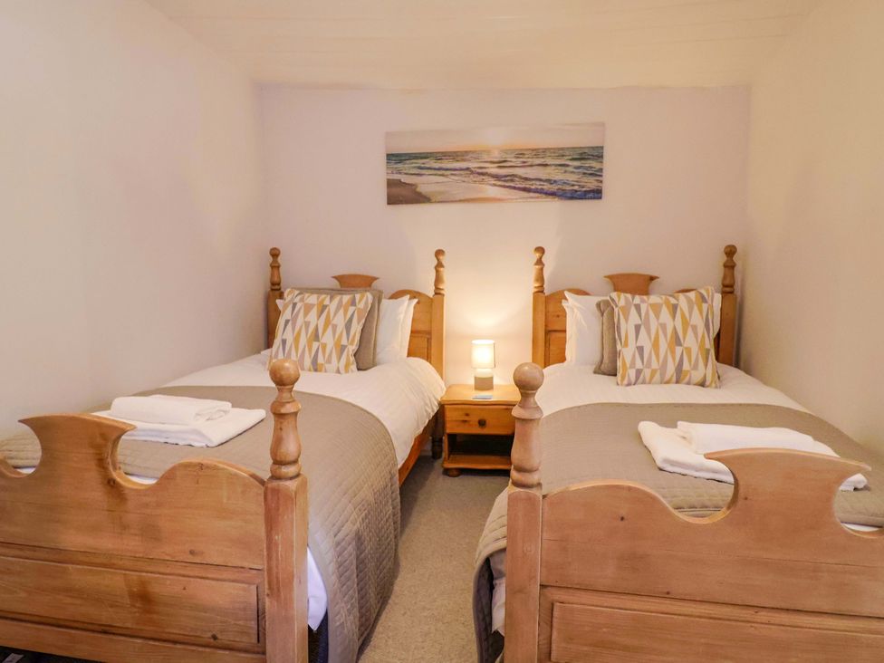 A bedroom with two beds and a bedside table at Bridge Cottage in Chideock