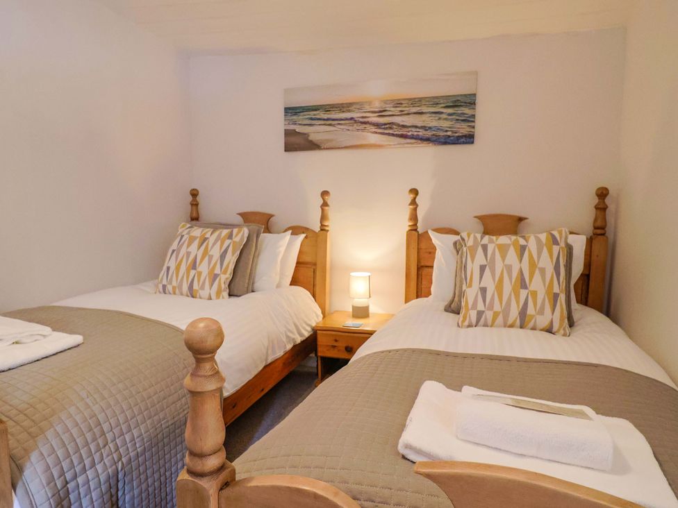 A bedroom with two beds and a lamp at Bridge Cottage in Chideock