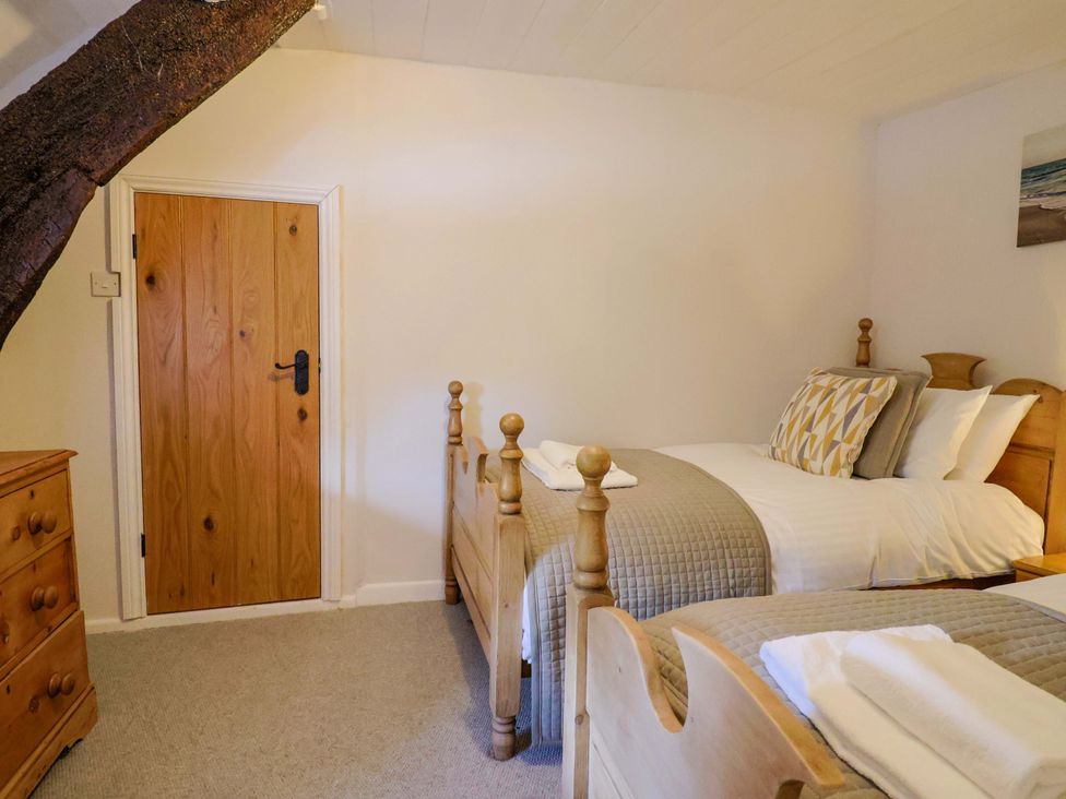 A bedroom with two beds and a wooden dresser at Bridge Cottage in Chideock