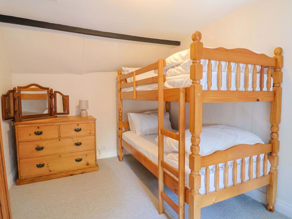 A bedroom with a bunk bed and a chest of drawers at Bridge Cottage in Chideock