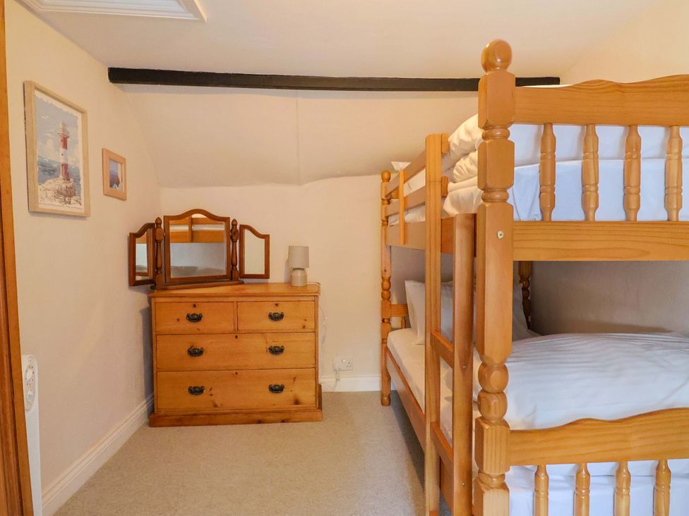 A bedroom with a bunk bed and a dresser at Bridge Cottage in Chideock