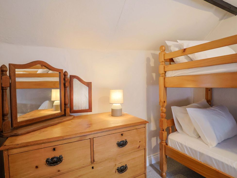 A bedroom with a bunk bed and a wooden dresser at Bridge Cottage in Chideock