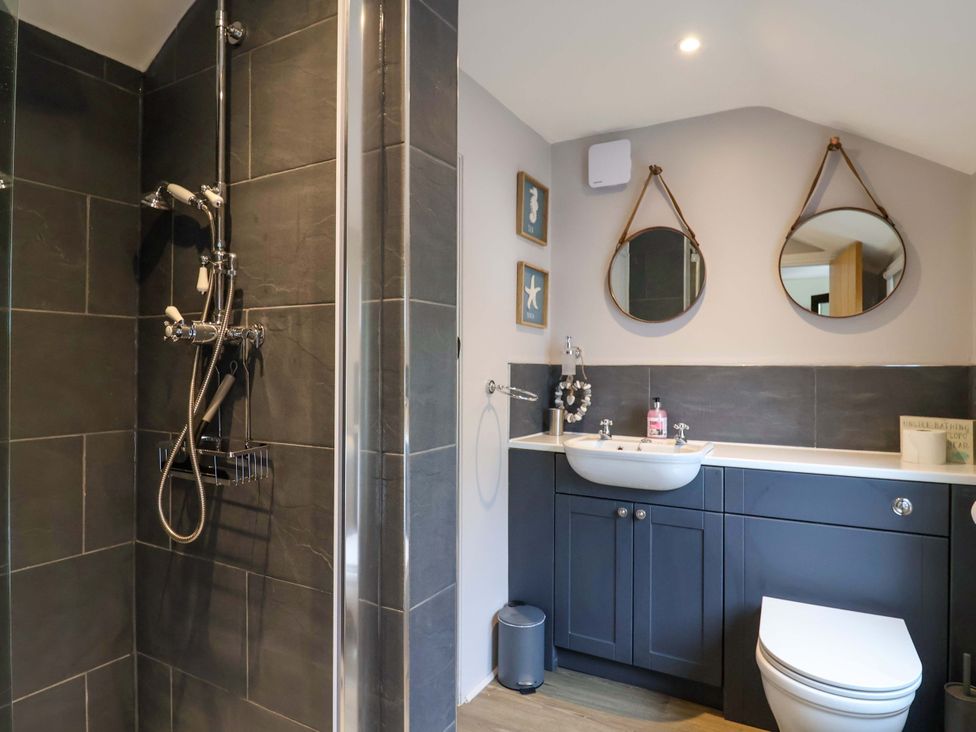 A bathroom with a shower, sink, and toilet at Bridge Cottage in Chideock