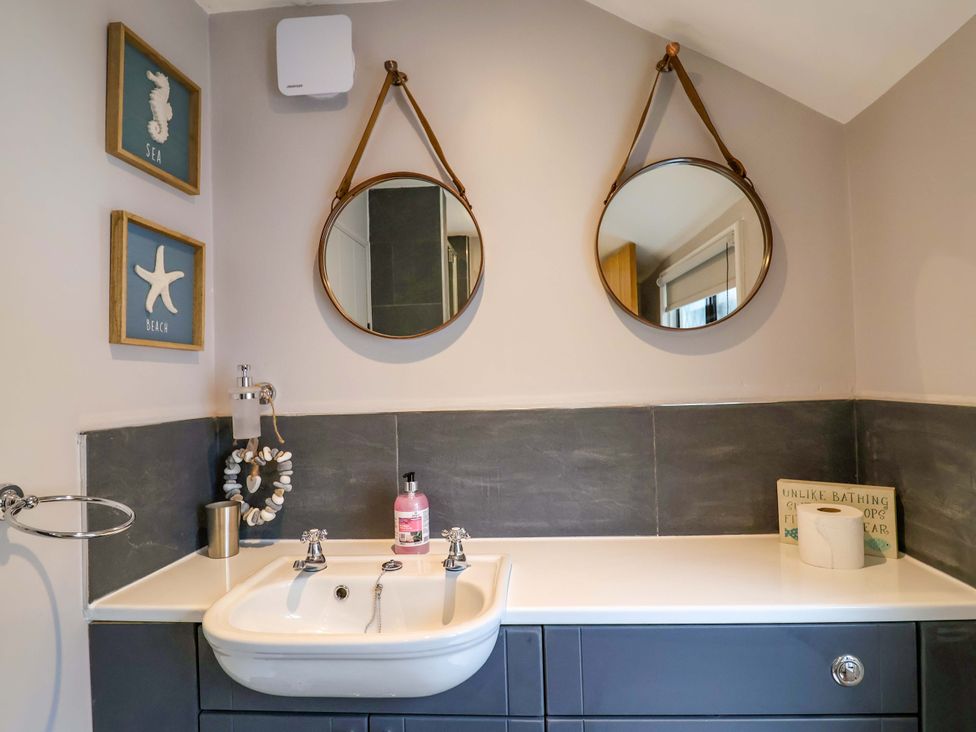 A bathroom with sink and mirrors at Bridge Cottage in Chideock