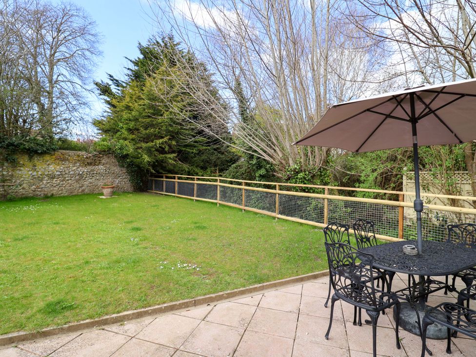 A garden with a table and chairs under an umbrella at Bridge Cottage in Chideock