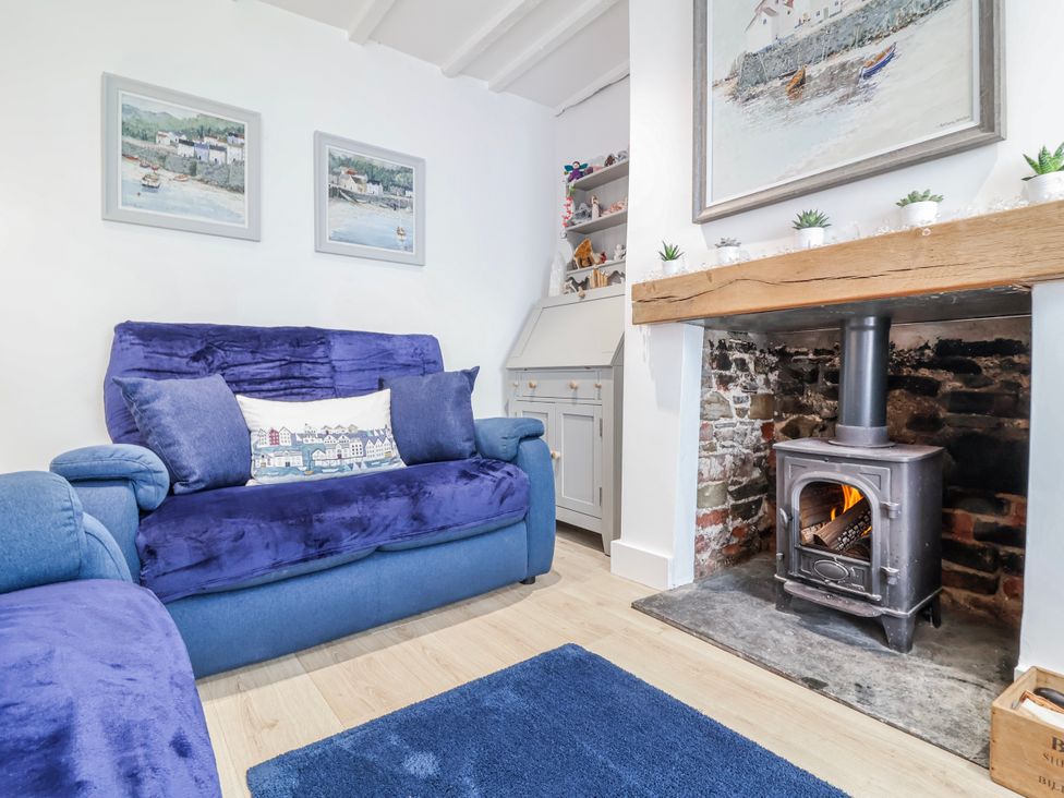 A living room with a wood stove and sofa at Hideaway Cottage