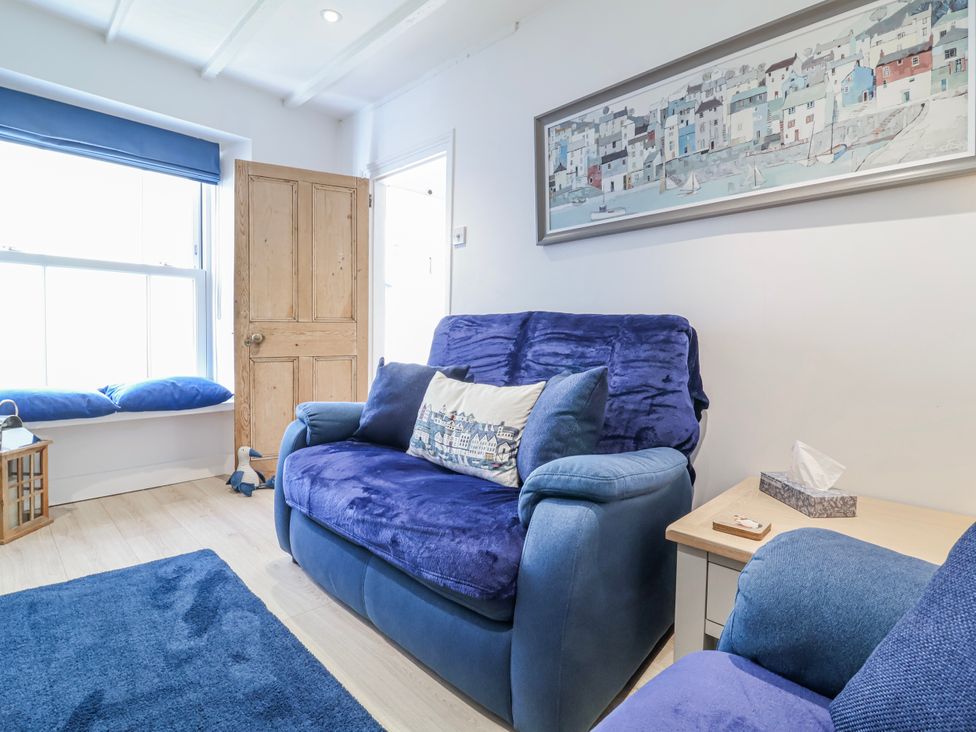 A living room with a blue sofa and a wooden door at Hideaway Cottage