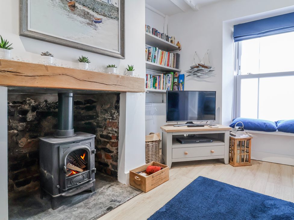 A living room with a stove and a television at Hideaway Cottage
