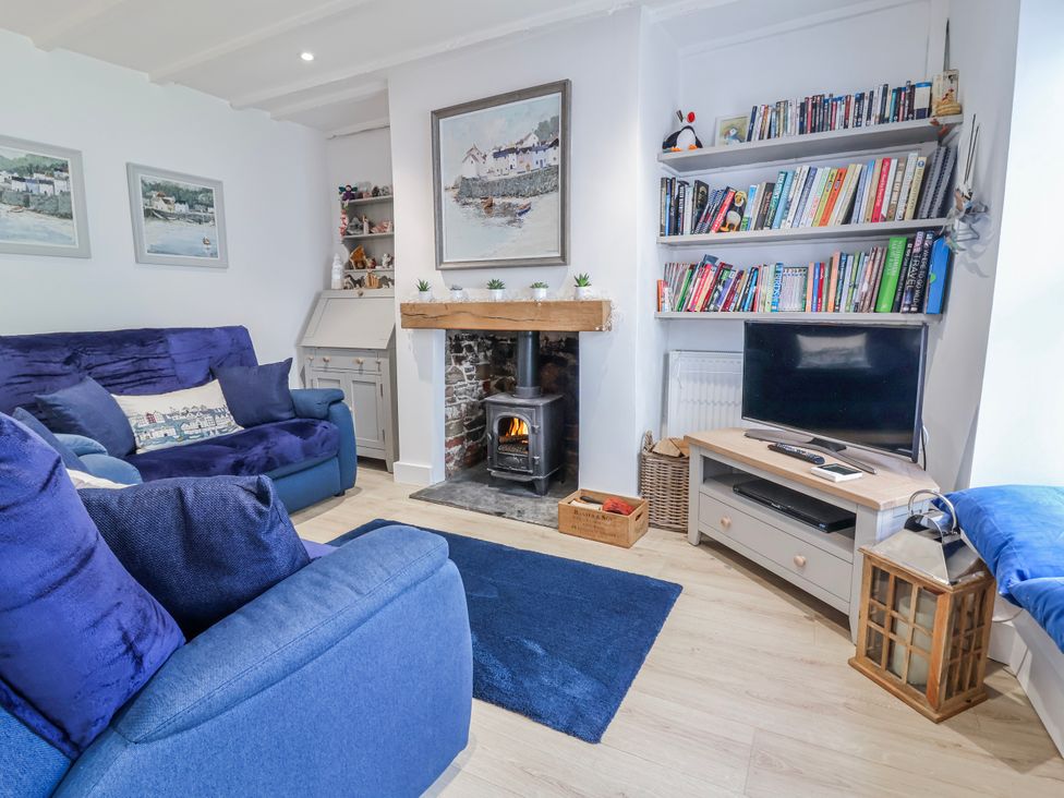 A living room with a fireplace and bookshelf at Hideaway Cottage 