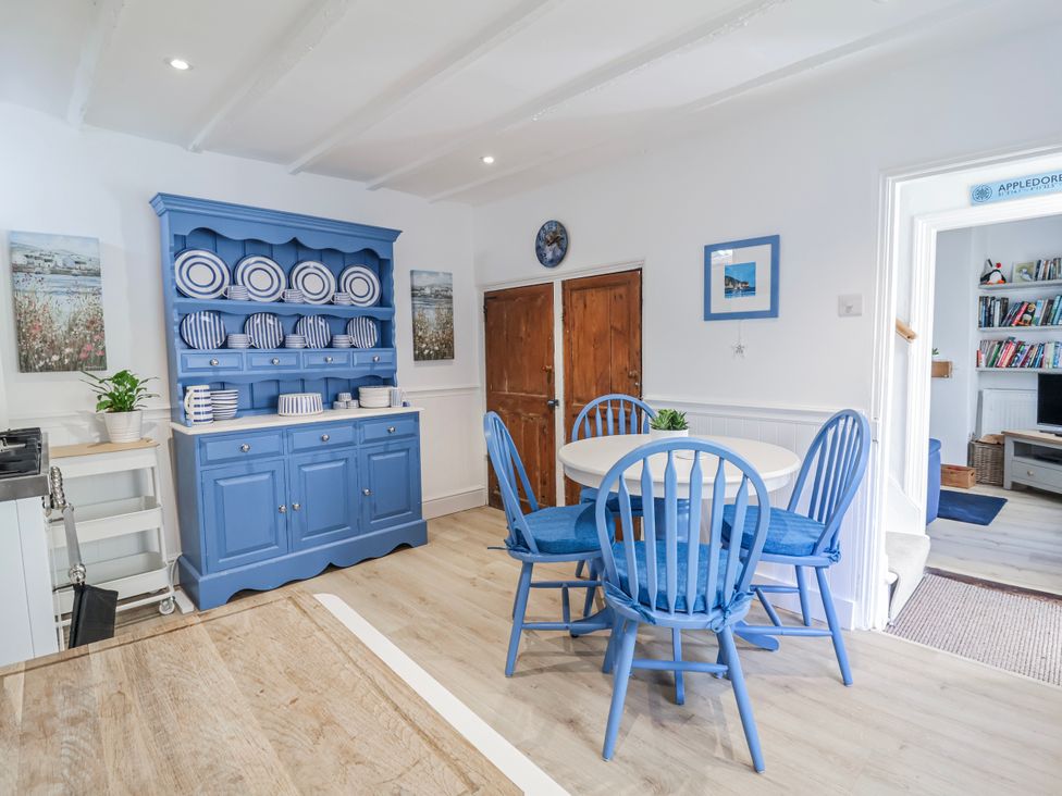 A dining room with a blue table and chairs at Hideaway Cottage