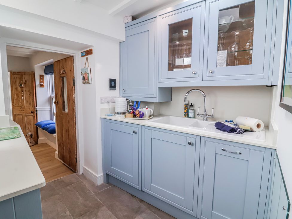 A kitchen with cabinets and sink at Hideaway Cottage