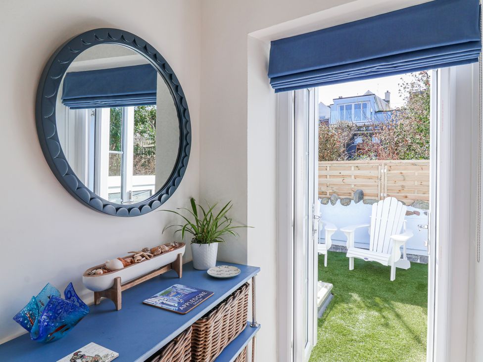 A living room with a mirror and a plant at Hideaway Cottage