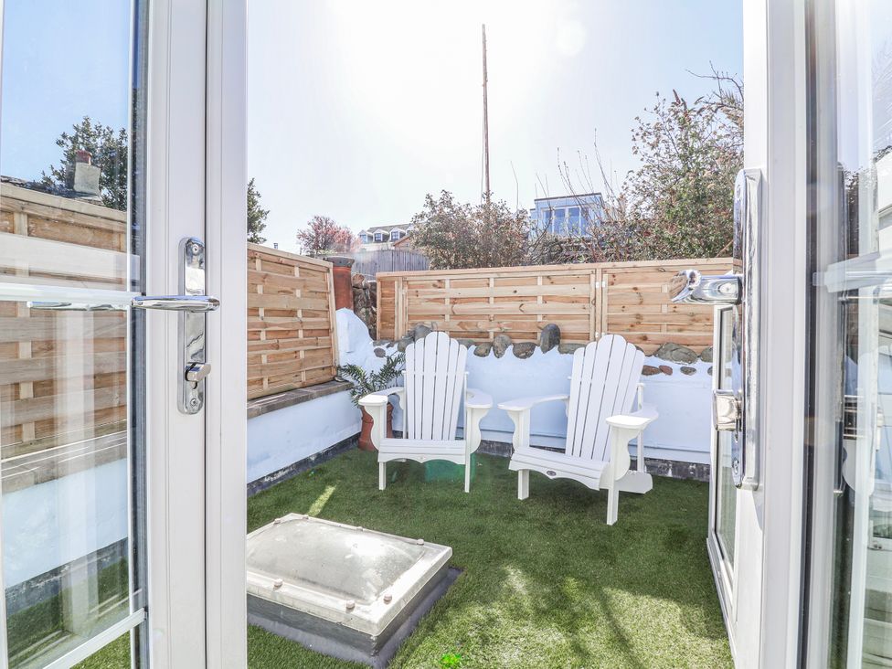 A garden with two chairs and grass at Hideaway Cottage
