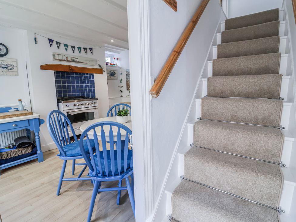 A kitchen with a table and chairs and a staircase at Hideaway Cottage 
