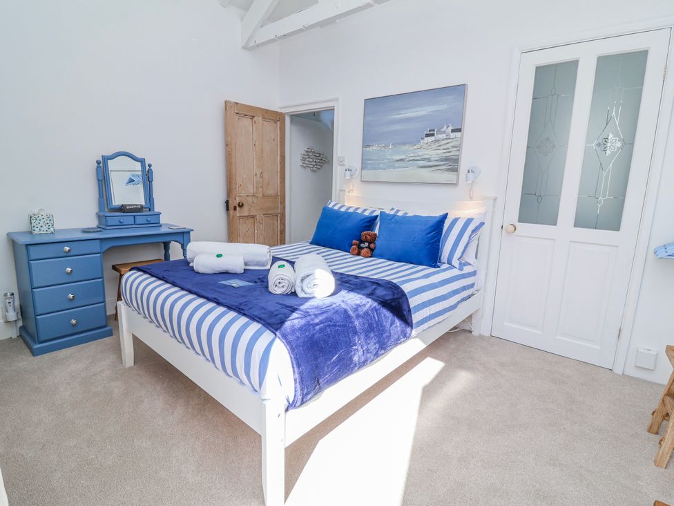 A bedroom with a bed and dresser at Hideaway Cottage