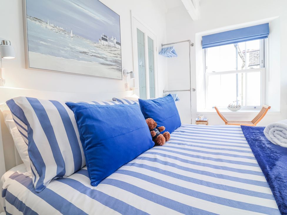 A bedroom with a striped bed and a teddy bear at Hideaway Cottage