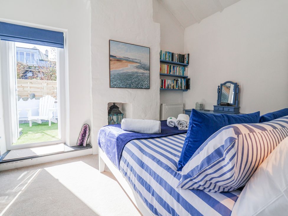 A bedroom with a bed and bookshelf at Hideaway Cottage