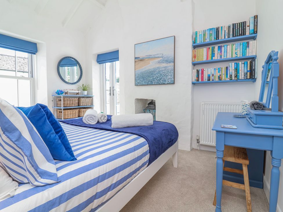 A bedroom with bookshelves and a mirror at Hideaway Cottage in 