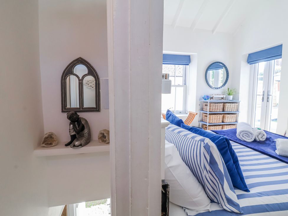 A bedroom featuring a bed with blue stripes and pillows at Hideaway Cottage