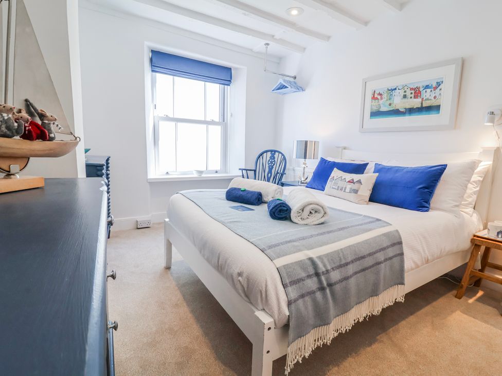 A bedroom with a bed and a window at Hideaway Cottage