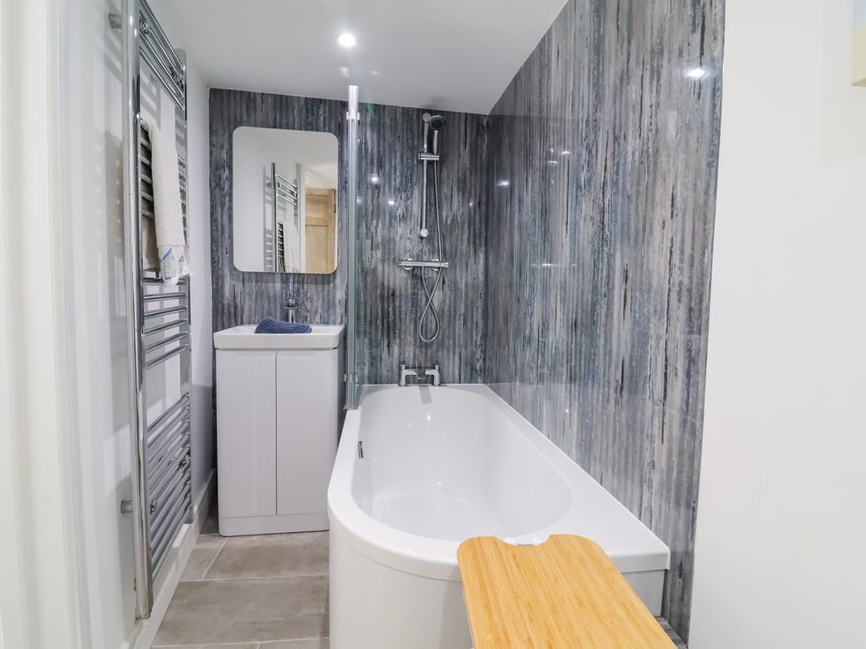 A bathroom with a bathtub and sink at Hideaway Cottage