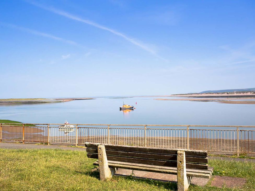 A waterfront view with a bench and boats at Hideaway Cottage