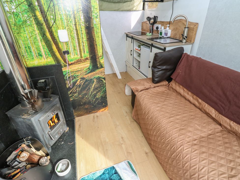 A living room with a wood stove and kitchen counter at The Horse Box in Blaydon-on-Tyne