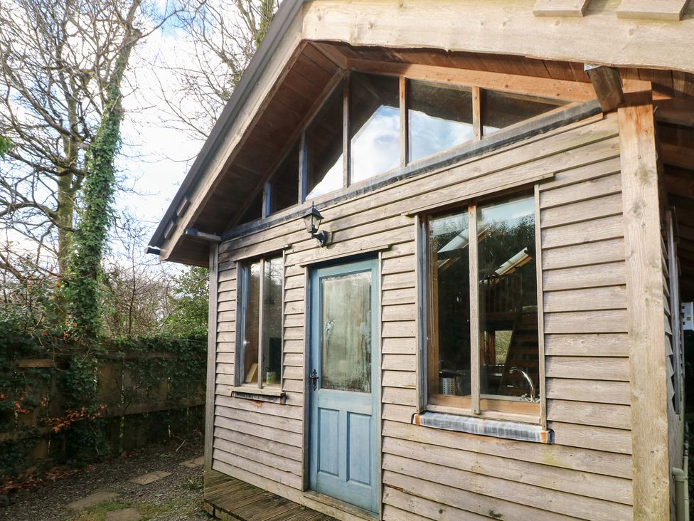 A wooden cabin with a blue door and large windows at the Cabin in Newport