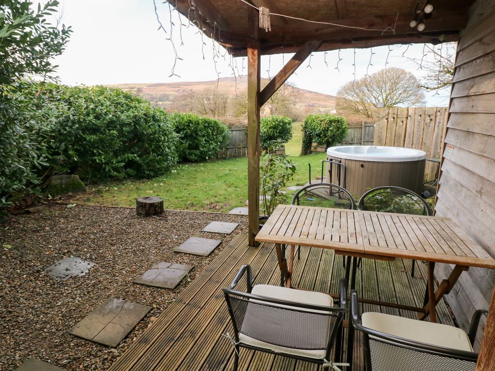 A garden with a table, chairs, hot tub and gravel at Cabin in Newport