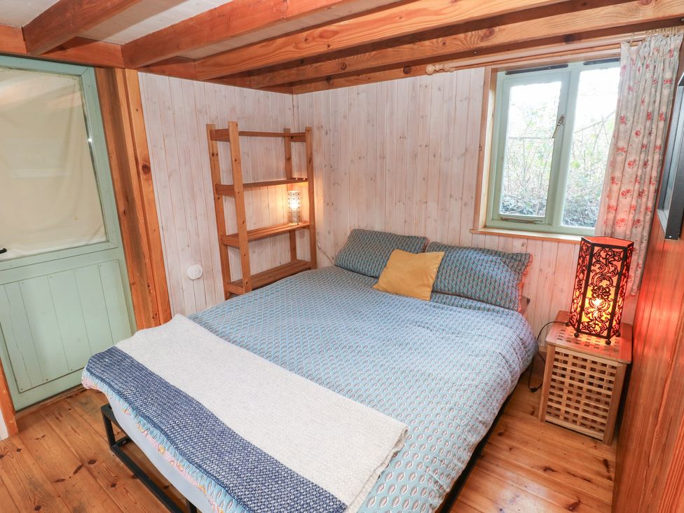 A bedroom with a bed and wooden shelf at Cabin in Newport