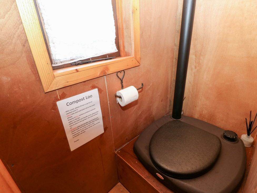 A compost toilet with a sign and a window at Cabin in Newport