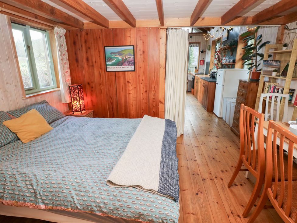 A bedroom with a bed and kitchen area at Cabin in Newport