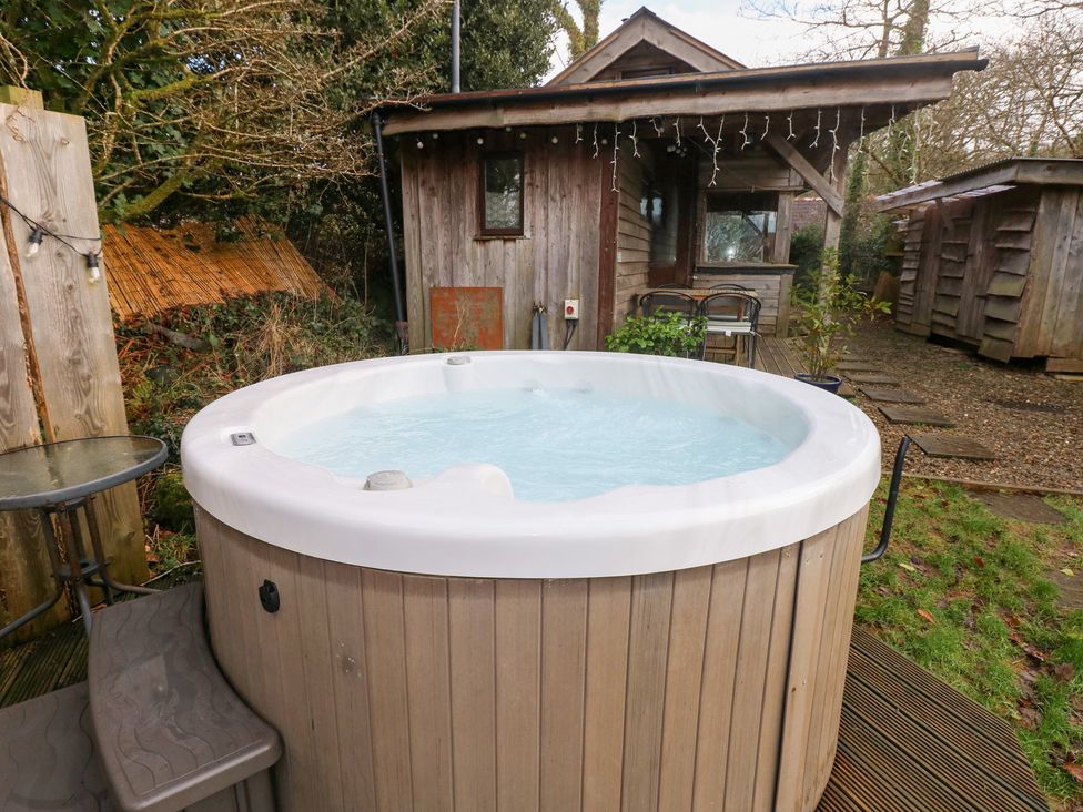 A hot tub near a wooden cabin at Cabin in Newport