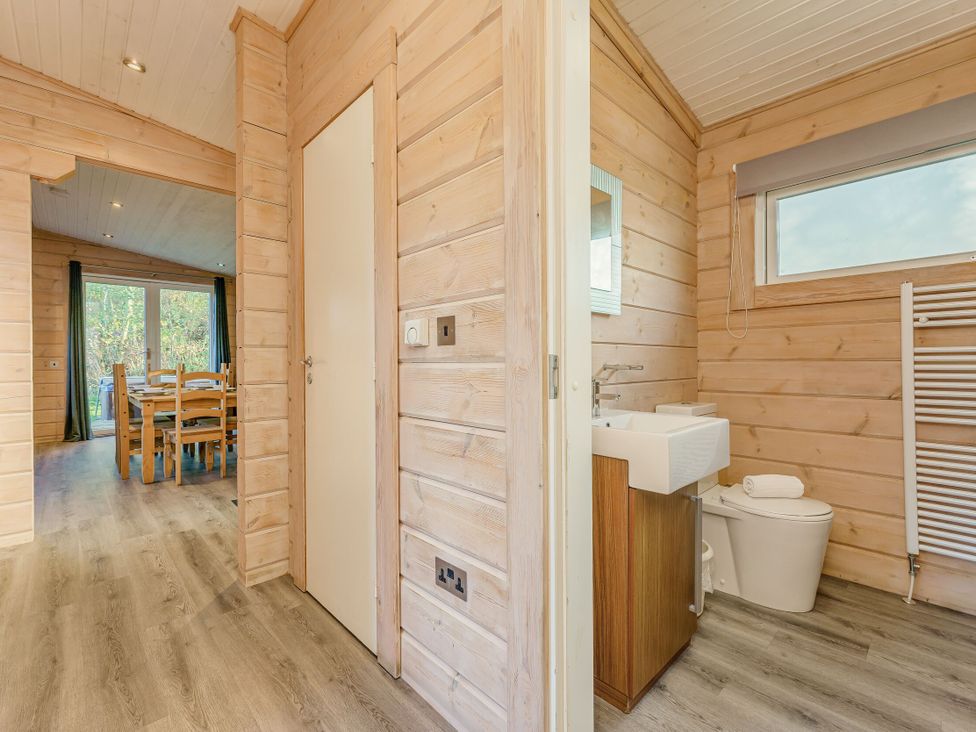 A bathroom with a toilet and sink leading to a dining area at Poplar Lodge (Pet) Thirsk