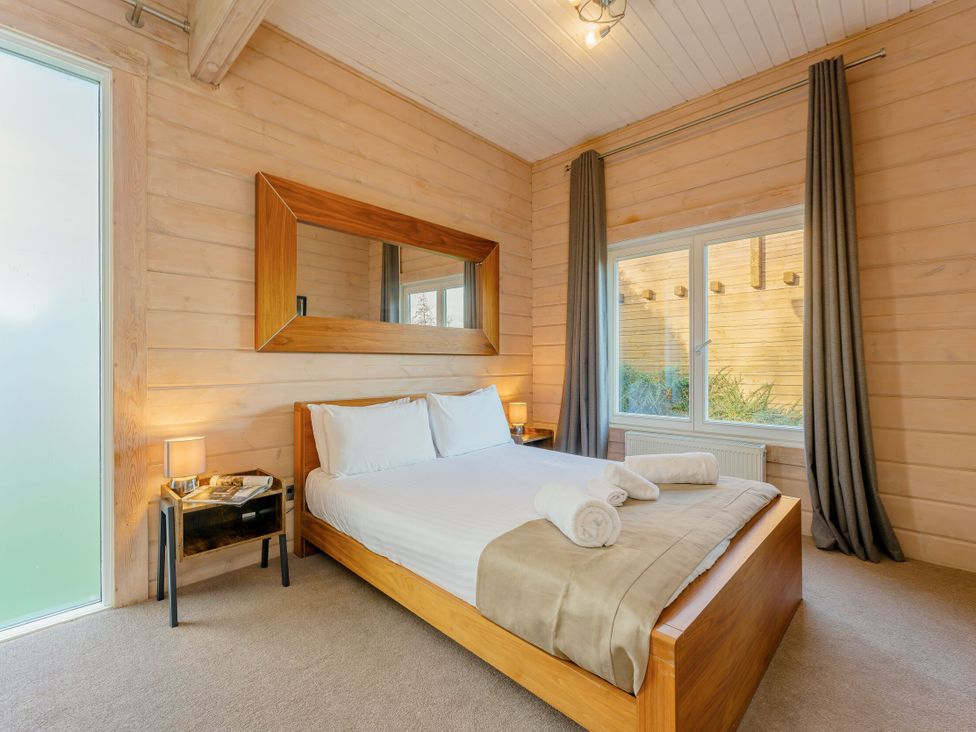 A bedroom with a bed and mirror at Poplar Lodge (Pet) Thirsk