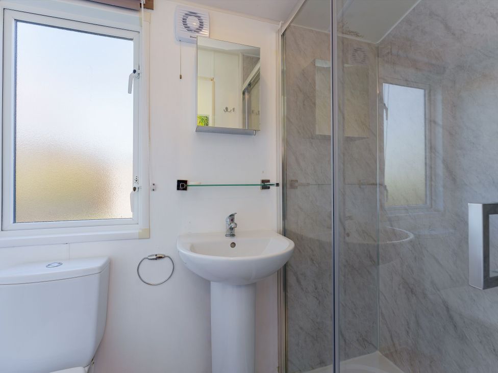 A bathroom with a shower, sink, and window at Spruce Waterside Spa (Pet) Thirsk