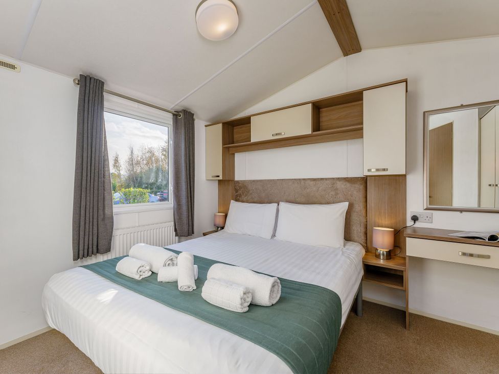 A bedroom with a bed and window at Spruce Waterside Spa (Pet) Thirsk