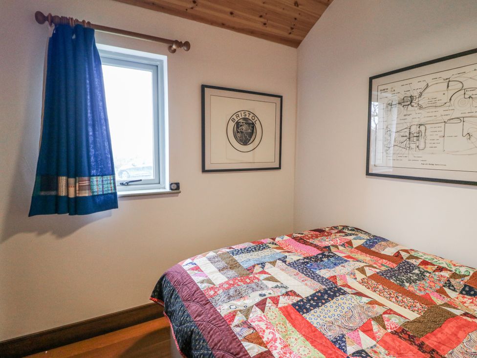 A bedroom with a quilted bed and framed art at The Faithfuls Cabin in Dingle