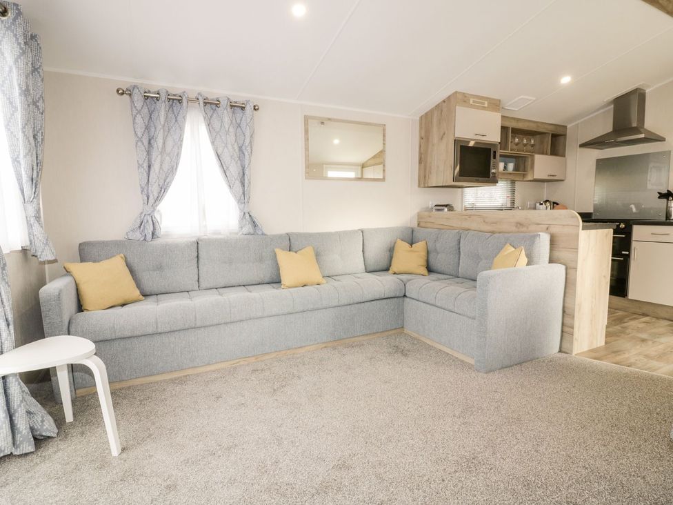 A living room with a sofa and kitchen setup at Barney's Retreat in Newquay