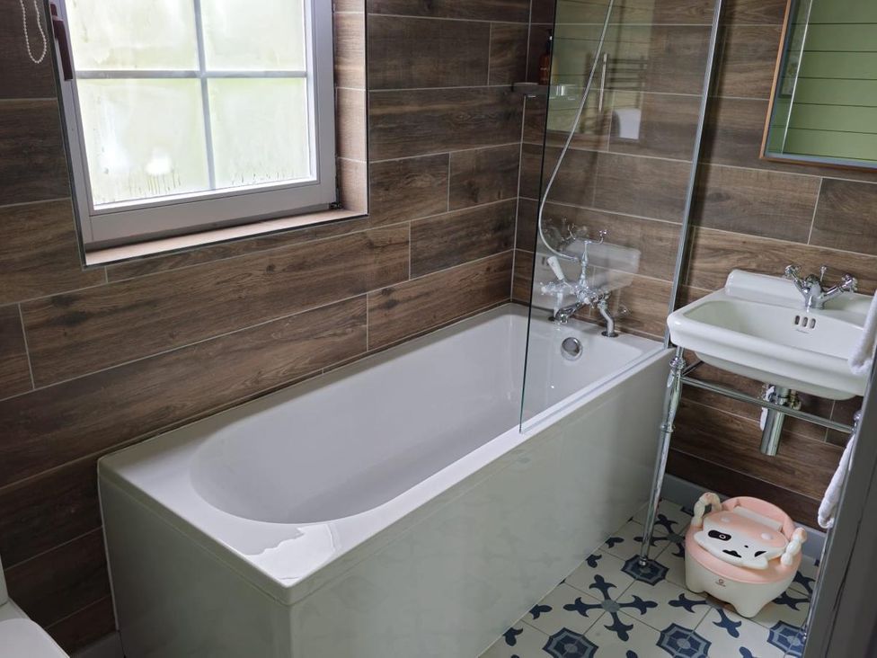 A bathroom with a bathtub, sink, and a shower glass panel at Kinder Lodge 3 in Portreath