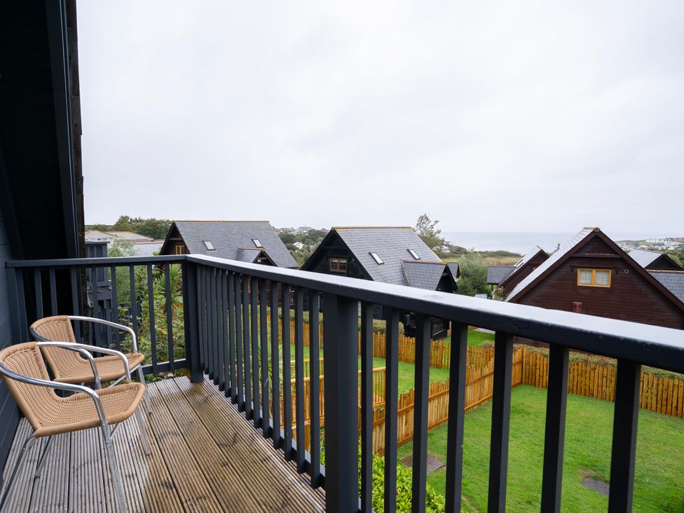 A balcony with chairs overlooking houses and a garden at Kinder Lodge 3 Spa (Pet) Redruth