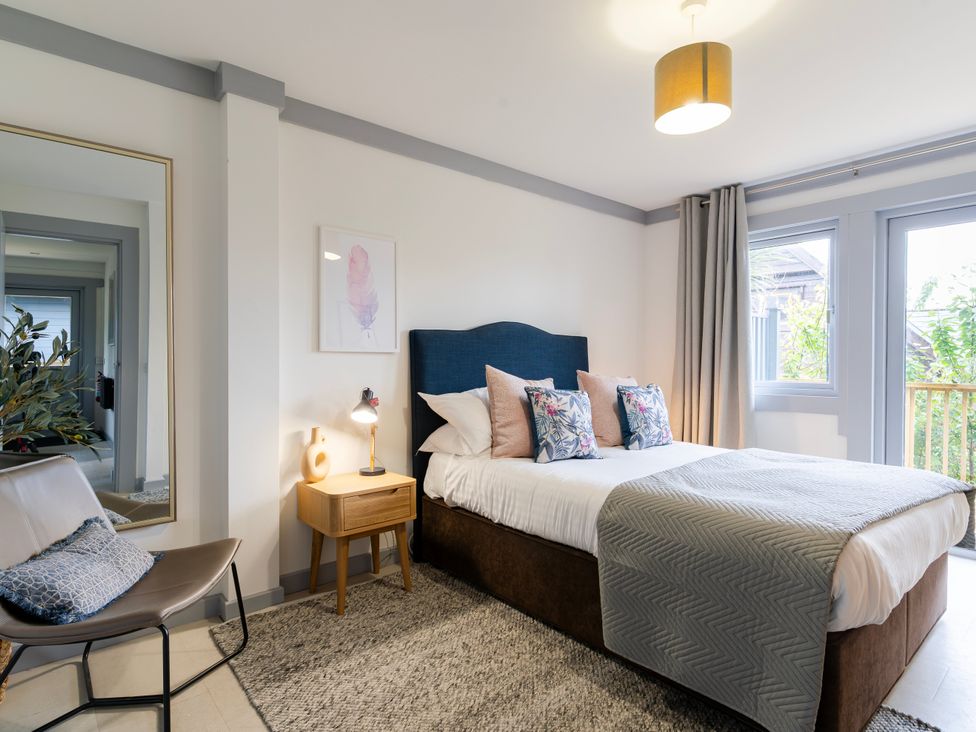 A bedroom with a bed and mirror at Kinder Lodge 3 Spa (Pet) Redruth